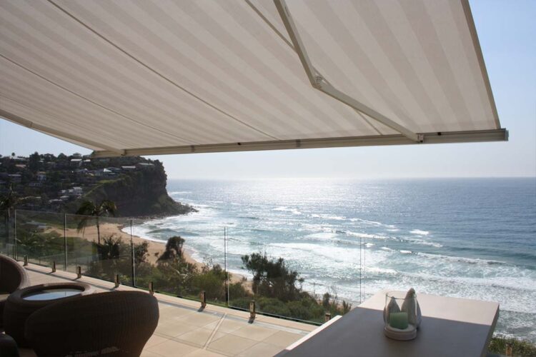 White retractable awning for balcony with view of the beach