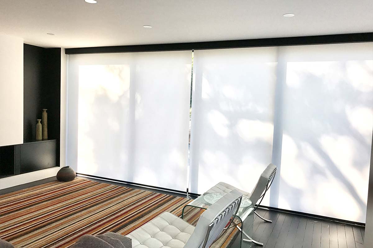 White motorised roller blinds covering windows in home