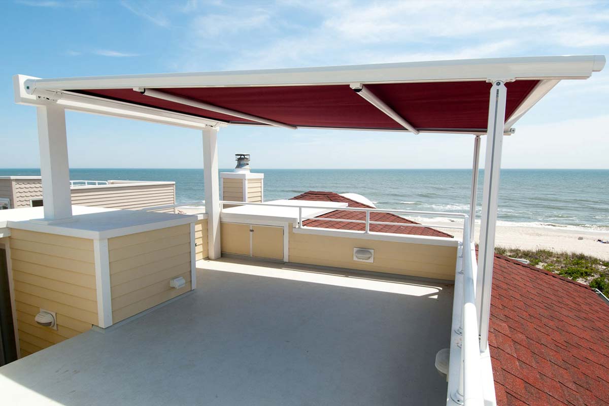 Red retractable pergola adding shade for rooftop with view of beach